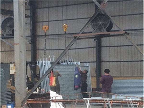 Die Arbeiter in der Verzinkungswerkstatt entladen die fertige temporäre Zaunplatte