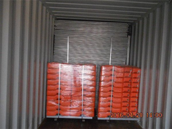 Paneles de valla temporales en palet cargados en contenedor con patas naranjas