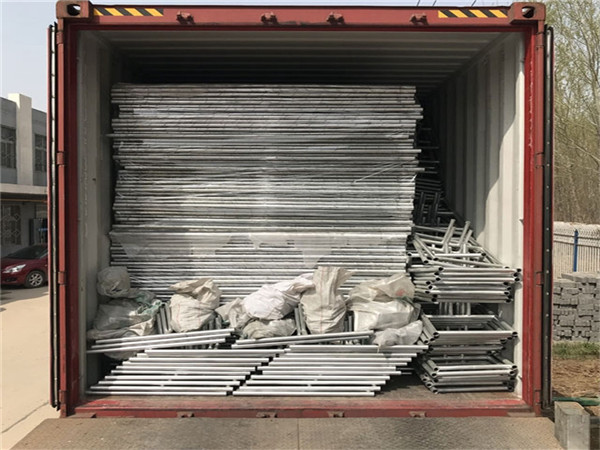 Temporary chain link fence panels in steel pallet loading into container by forklift