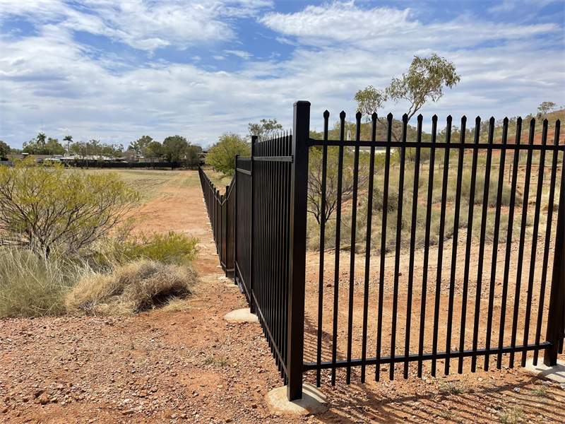 Weatherproof steel picket fence with a powder-coated finish, installed along a busy city sidewalk for pedestrian safety.