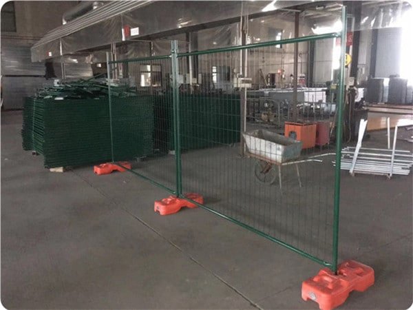 Green powder coated temporary fence panels installed with orange feet and green clamps in our workshop.