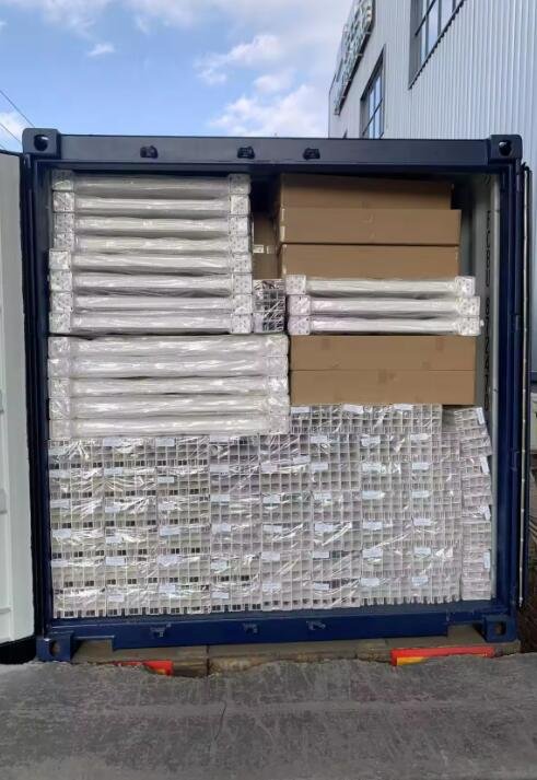 A shipping container filled with neatly stacked and packaged PVC horse arena fencing materials. The fencing components are wrapped in plastic and organized in various layers, showcasing the efficient use of space for transportation. The container is ready for shipment, highlighting the well-prepared and protected fencing products.