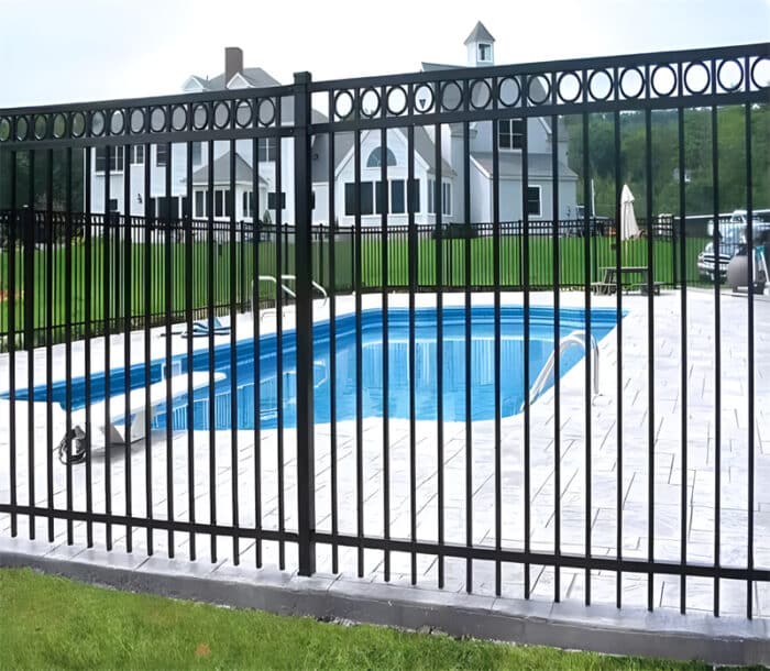 Black aluminum flat top fence with decorative rings installed around a residential swimming pool, providing safety and a stylish appearance.