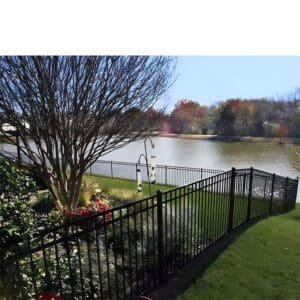 Black aluminum flat top fence surrounding a scenic lakefront backyard, providing safety and an unobstructed view of the water and autumn foliage.