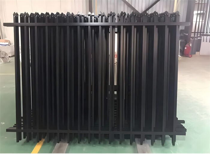 Stacked black aluminum spear top fence panels in a warehouse, ready for shipment.