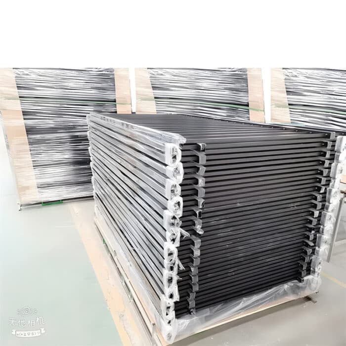 Stacks of packaged black aluminum flat top fence panels in a warehouse, ready for shipment.