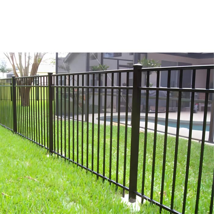 Black aluminum fence installed around a lush garden with blooming flowers and tall trees, enhancing both security and aesthetics.