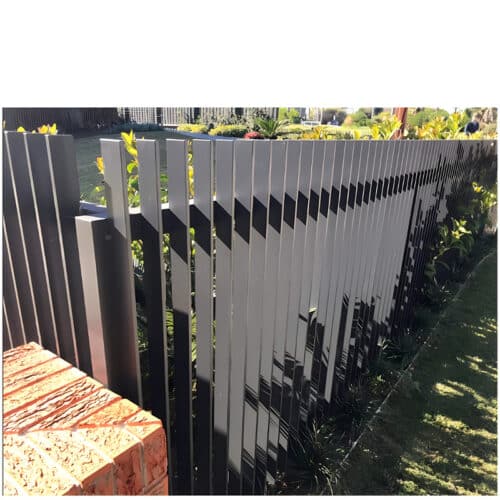 Black aluminium blade fence installed along a garden, offering modern aesthetics and security with vertical slats.