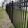 A long stretch of black aluminum spear top fencing installed along the perimeter of a residential property.