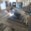 Worker welding parts of a stillage cage, showcasing the manufacturing process.