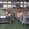 Industrial warehouse filled with multiple stacked stillage cages containing various goods.