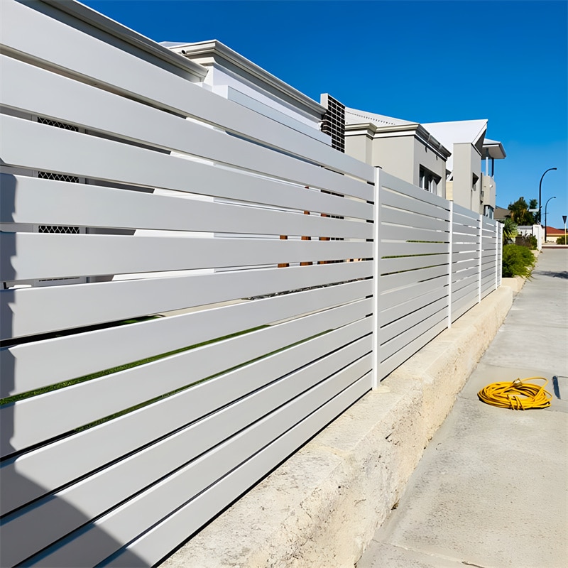 Clean white aluminium slat fence installed along a residential area, showcasing horizontal slats and providing privacy and style.