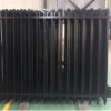 Stacked black aluminum spear top fence panels in a warehouse, ready for shipment.