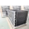 Stacks of packaged black aluminum flat top fence panels in a warehouse, ready for shipment.