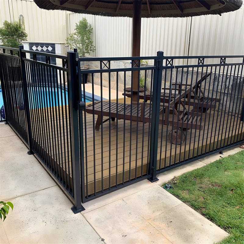 Black aluminum flat top fence with decorative rings installed around a garden pool area, surrounded by lush greenery and palm trees.