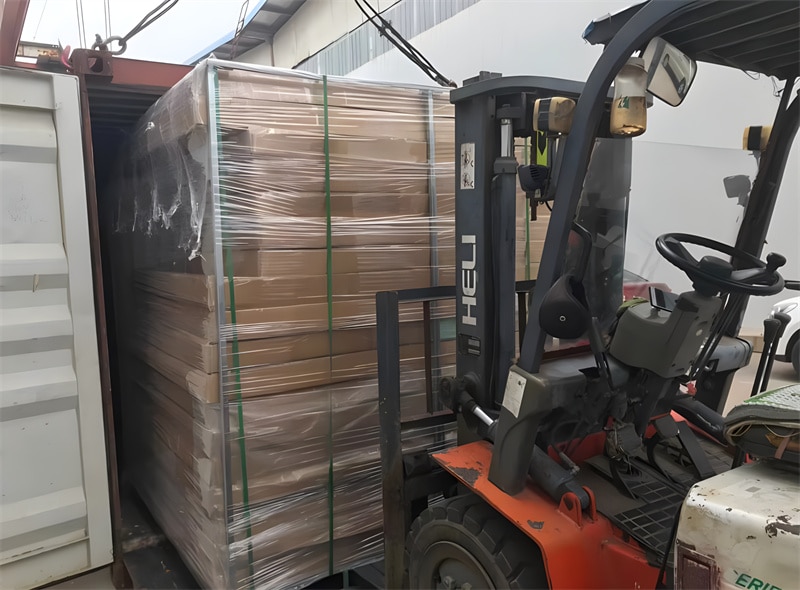 A forklift loading a large pallet of packaged aluminium fencing materials into a shipping container, showcasing the preparation for delivery and export.