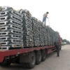 Truck loaded with stacked, collapsible stillage cages being secured for transport by workers.