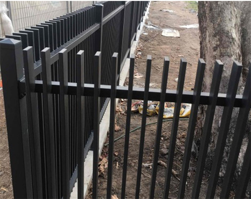 Close-up view of a black aluminium blade fence installed along a pathway, highlighting the vertical slats and sturdy construction.