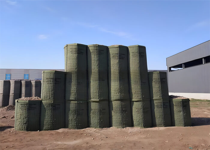 Stacked green Hesco barriers filled with gravel, ready for deployment.