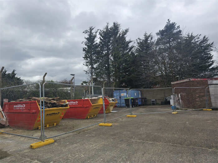 Yellow ballast blocks and temporary fence panels are installed together.