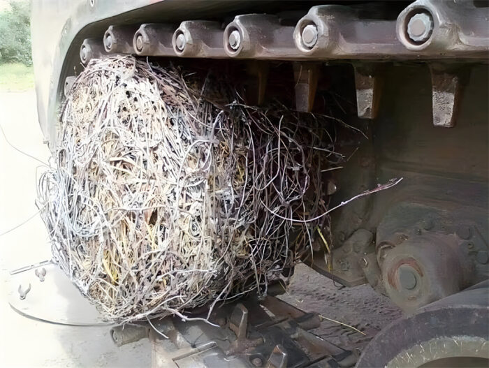 Gros plan d'une chenille de char emmêlée dans un grillage métallique, immobilisant efficacement le véhicule en enveloppant les chenilles, démontrant l'efficacité du grillage de chenille de char comme barrière antichar.