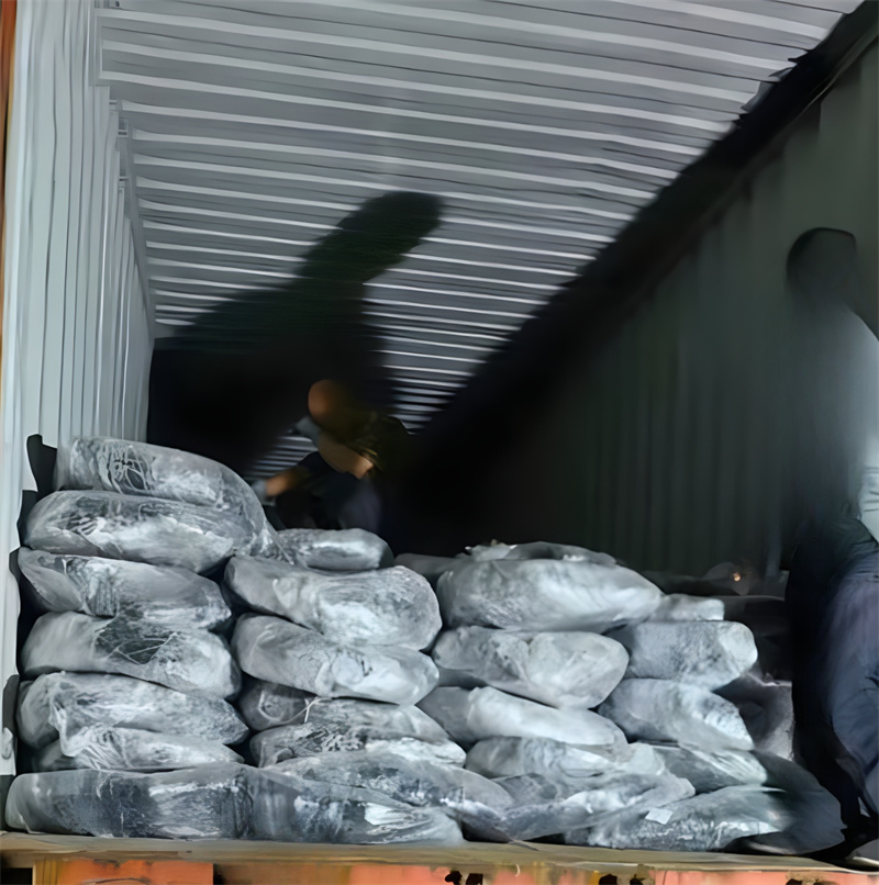 Workers loading wrapped tank track mesh bundles into a container, preparing for transportation. The image shows the durable packaging of the product, ensuring safe delivery to its destination.