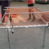 The workers are tying the wire to the frame tube of construction barrier fence.