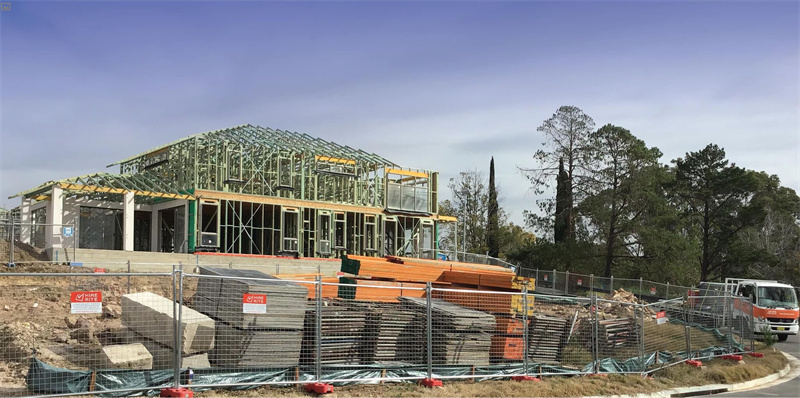 Temporary fencing enclosing a fire-damaged building site under repair with visible warning signage.