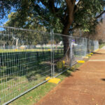 Temporary fencing along a sidewalk with yellow bases.