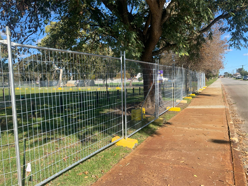 Temporary fencing along a sidewalk with yellow bases.