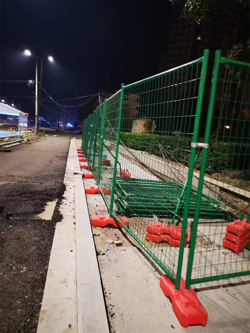 Night view of a construction area secured with temporary fencing and bright lighting.