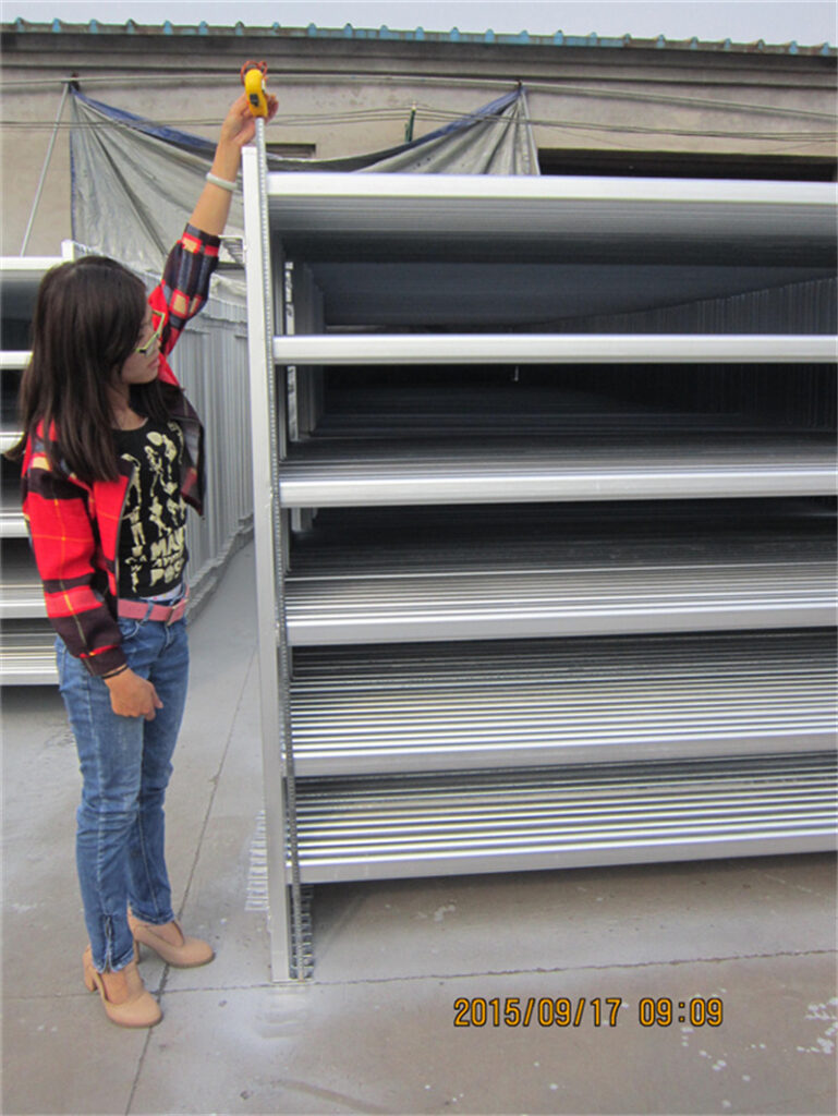 A professional inspecting the height and width of a 1.8m x 2.1m galvanized cattle panel to ensure precise specifications.