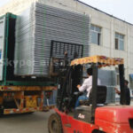 Forklift loading galvanized cattle panels into a shipping container for wholesale delivery.