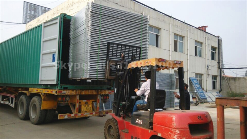 Forklift loading galvanized cattle panels into a shipping container for wholesale delivery.