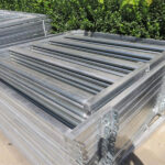 A stack of 1.8m x 2.1m heavy-duty galvanised cattle yard panels, neatly packed for shipment, demonstrating efficient storage and transport solutions.