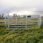 Heavy-duty galvanised stockyard panels installed in a lush green field, designed to withstand harsh weather conditions while providing secure containment for livestock.