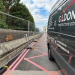 Construction site with temporary fencing set up beside a van, featuring marked pathways for efficient access.