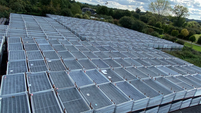 Large outdoor storage area filled with stacked metal fencing panels.