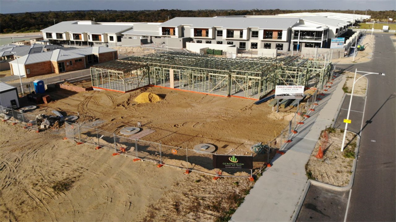 Construction site with temporary fencing and orange bases, surrounded by residential buildings.