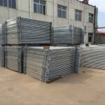 Stacks of galvanized portable horse corral panels neatly arranged outside a factory, showcasing their durability and readiness for bulk shipping.