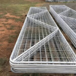 A view of several stacked galvanized farm gates with a grid pattern, waiting for delivery or installation, emphasizing their organized storage.