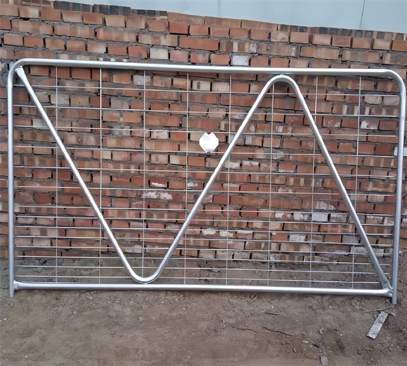 A galvanized gate with a diagonal brace set against a brick wall, showcasing its sturdy design and readiness for installation.