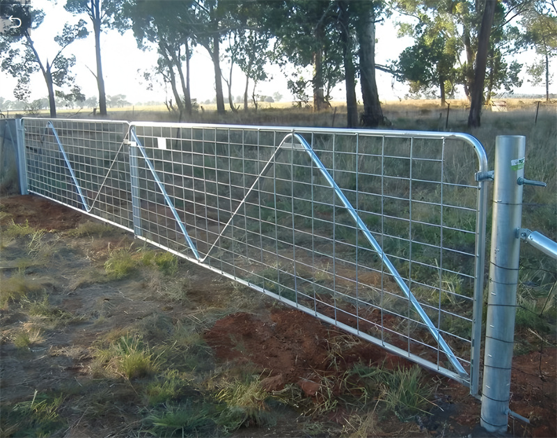 Installed galvanized mesh farm fence gate in a rural setting, demonstrating its functionality in livestock management.