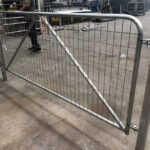 Galvanized mesh farm fence gate in a workshop setting, showcasing the quality and design of the gate before installation.