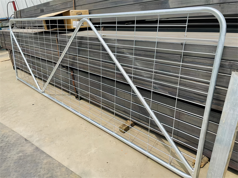 A flat-laying galvanized steel farm gate with a grid pattern, emphasizing its design and structure in a manufacturing environment, ready for installation.