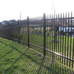 Black steel fence installed alongside a lawn, capturing the aesthetic appeal and structure of a residential perimeter.