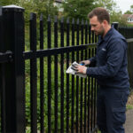 A worker conducting maintenance on a steel picket fence, demonstrating regular upkeep to ensure longevity and appearance.