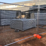 Stacked temporary fencing panels stored outdoors, ready for deployment.