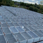 Aerial view of a large outdoor storage area filled with stacked temporary fencing panels, ready for deployment.