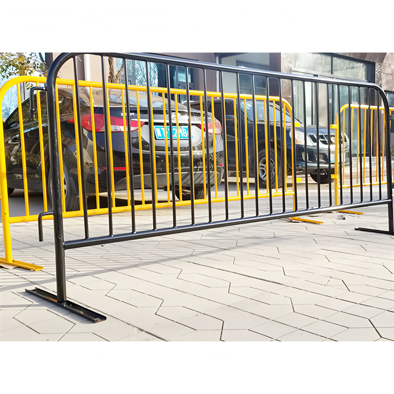 Black and yellow crowd barricade installed on a pavement, with cars parked in the background.